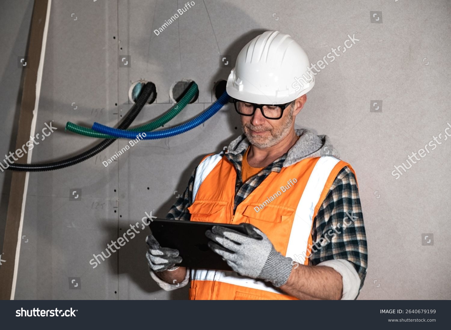 stock photo construction foreman in ppe using a digital tablet to check blueprints on an indoor jobsite with 2640679199