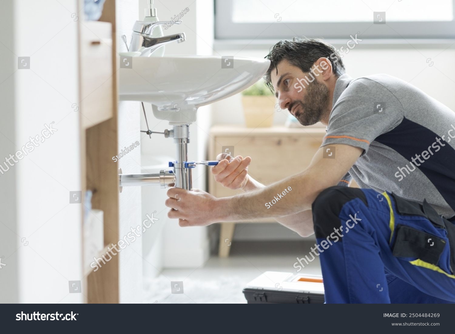 stock photo professional plumber fixing a bathroom sink using water pump pliers 2504484269