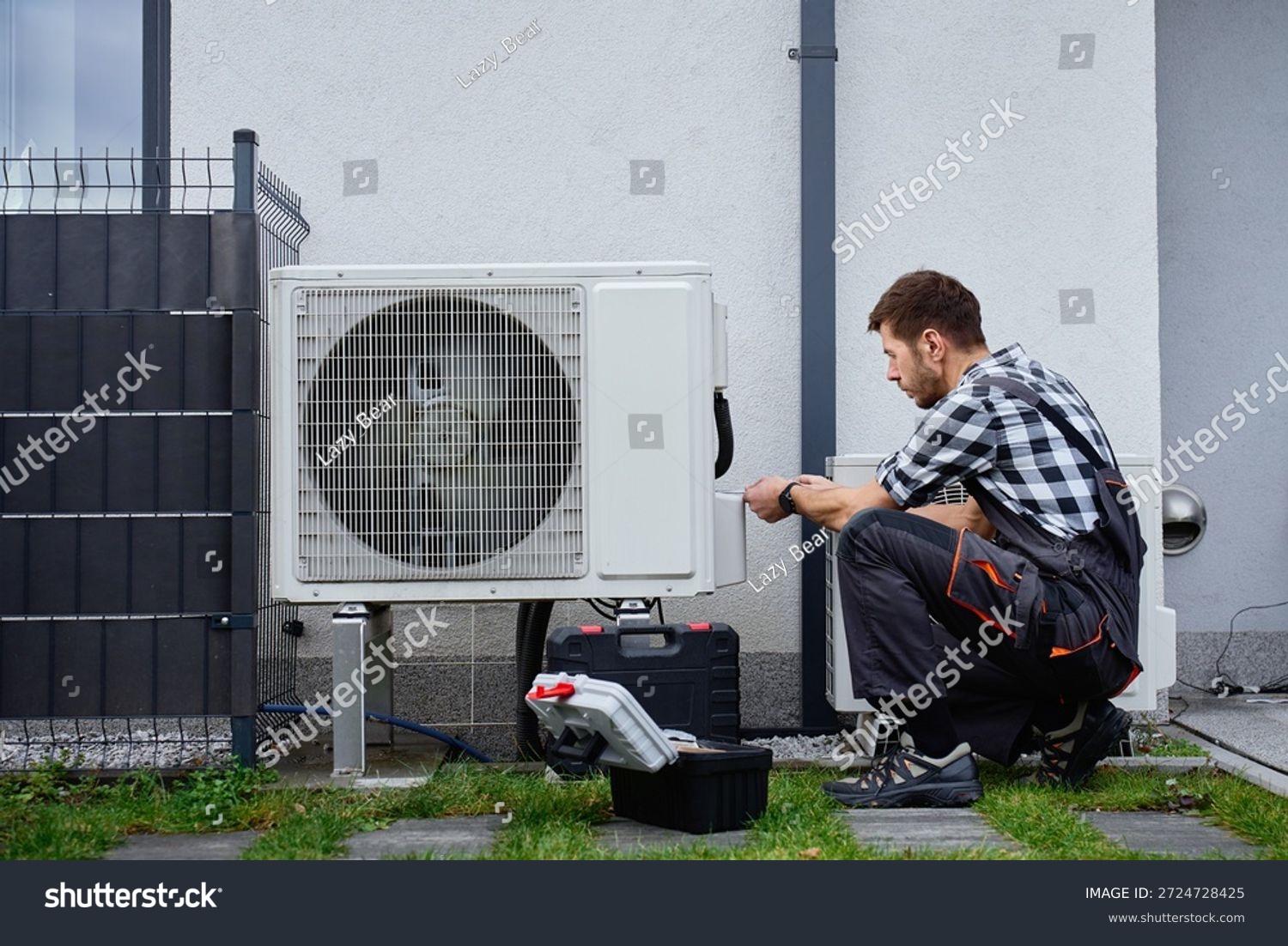 stock photo technician performing maintenance on outdoor heat pump unit near residential building exterior man 2724728425